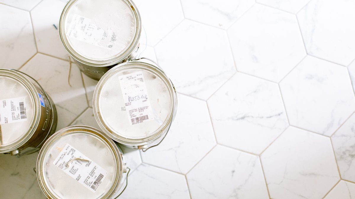 Gallon paint cans arranged on a hexagonal tile floor for project planning.